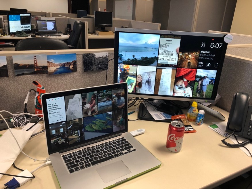 An office cubicle with a laptop, an external monitor, a desk phone and a can of soda