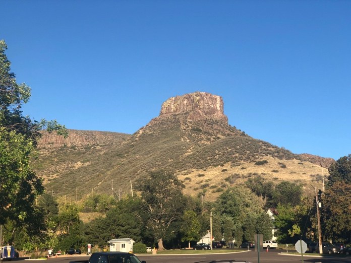 A flat-topped rock butte above a small town under a clear blue sky